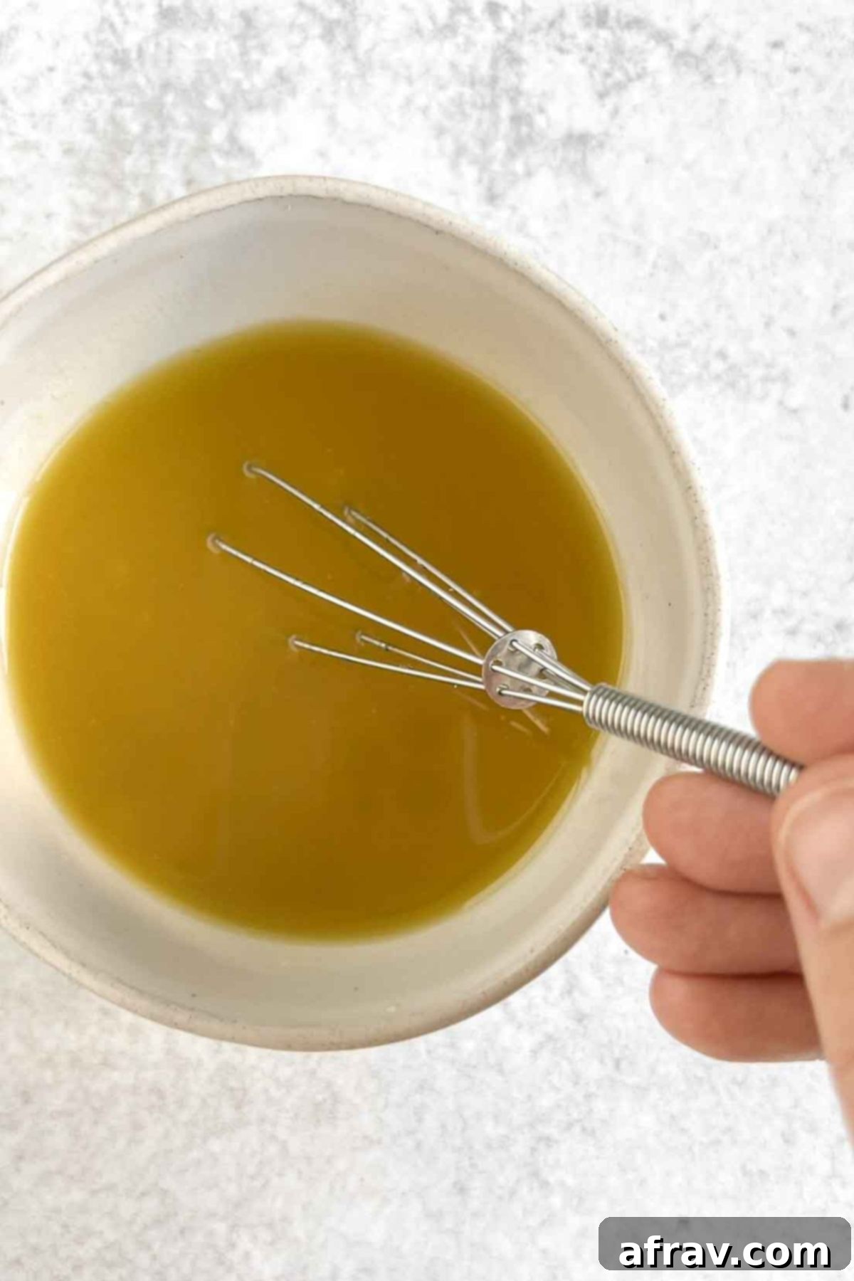 Harvest Quinoa Power Bowl 6 Hand holding a mini whisk in a small bowl mixing dressing.