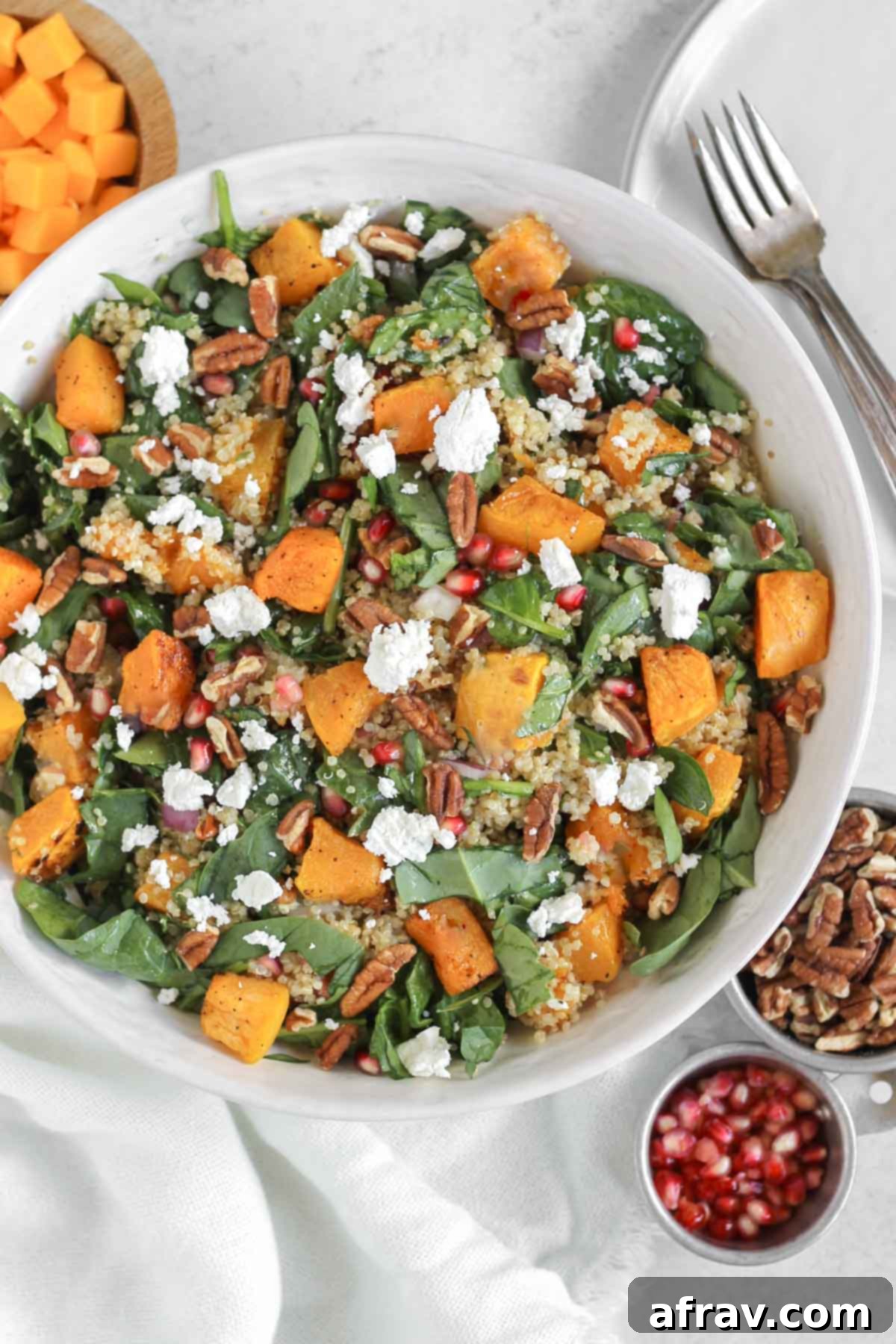 Harvest Quinoa Power Bowl 10 Fall quinoa salad with spinach in a serving bowl with pomegranate seeds, pecans, and squash in small bowls on the side.