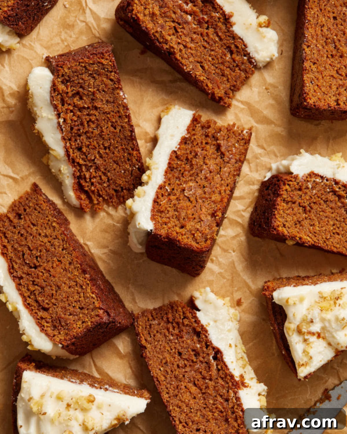 Overhead view of multiple slices of carrot cake arranged on crumpled brown parchment paper.