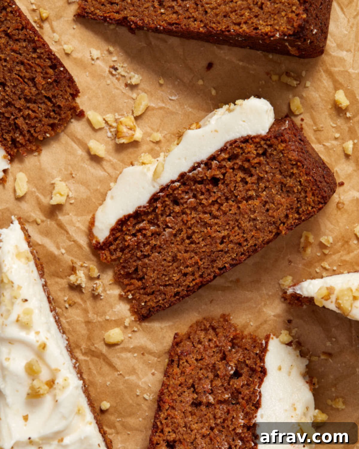 Overhead close up view of a slice of carrot cake on brown parchment paper.
