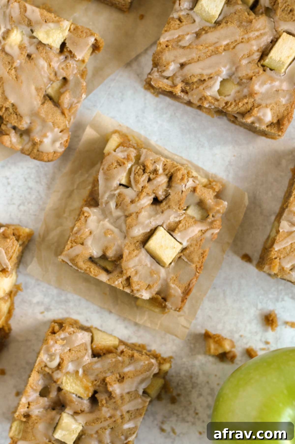 Cut-up apple blondie squares on a gray surface, showcasing their soft texture and maple glaze.