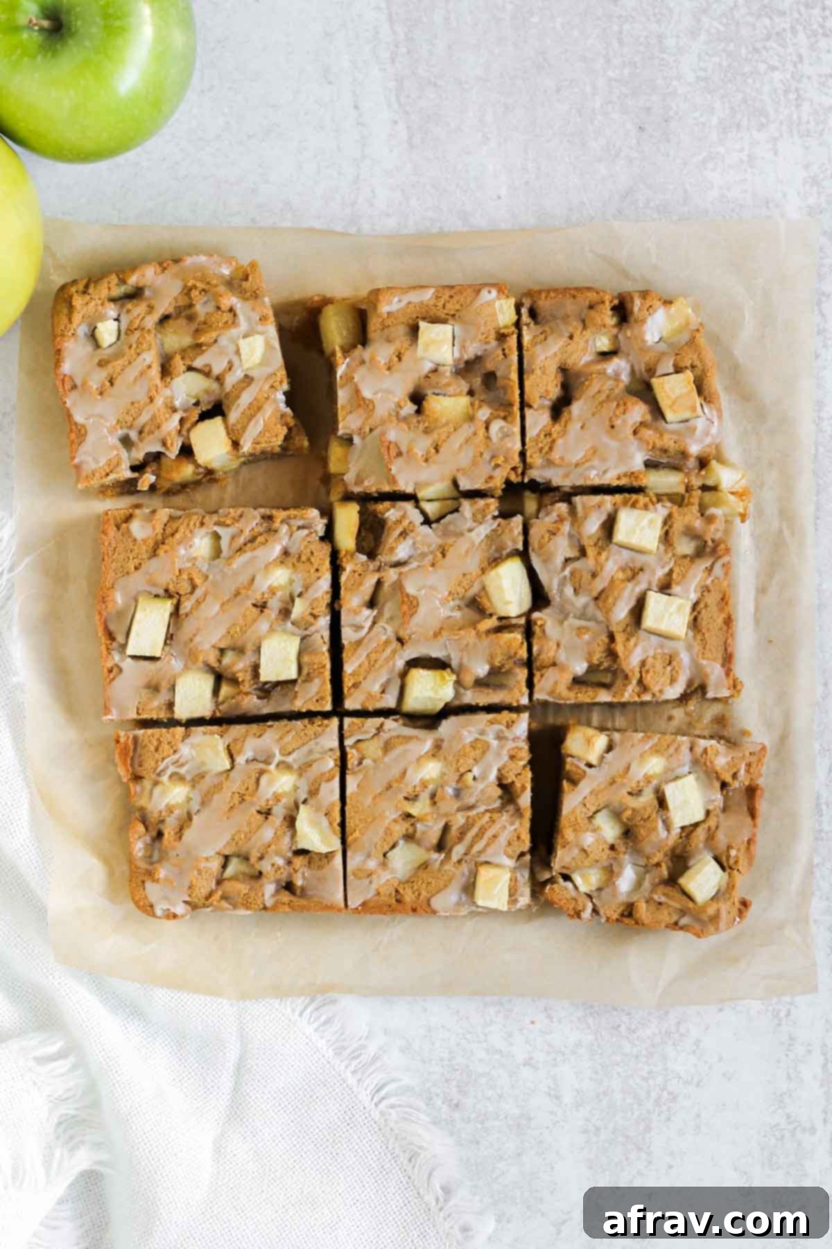 Perfectly cut apple blondie squares with sweet maple glaze, arranged on parchment paper.