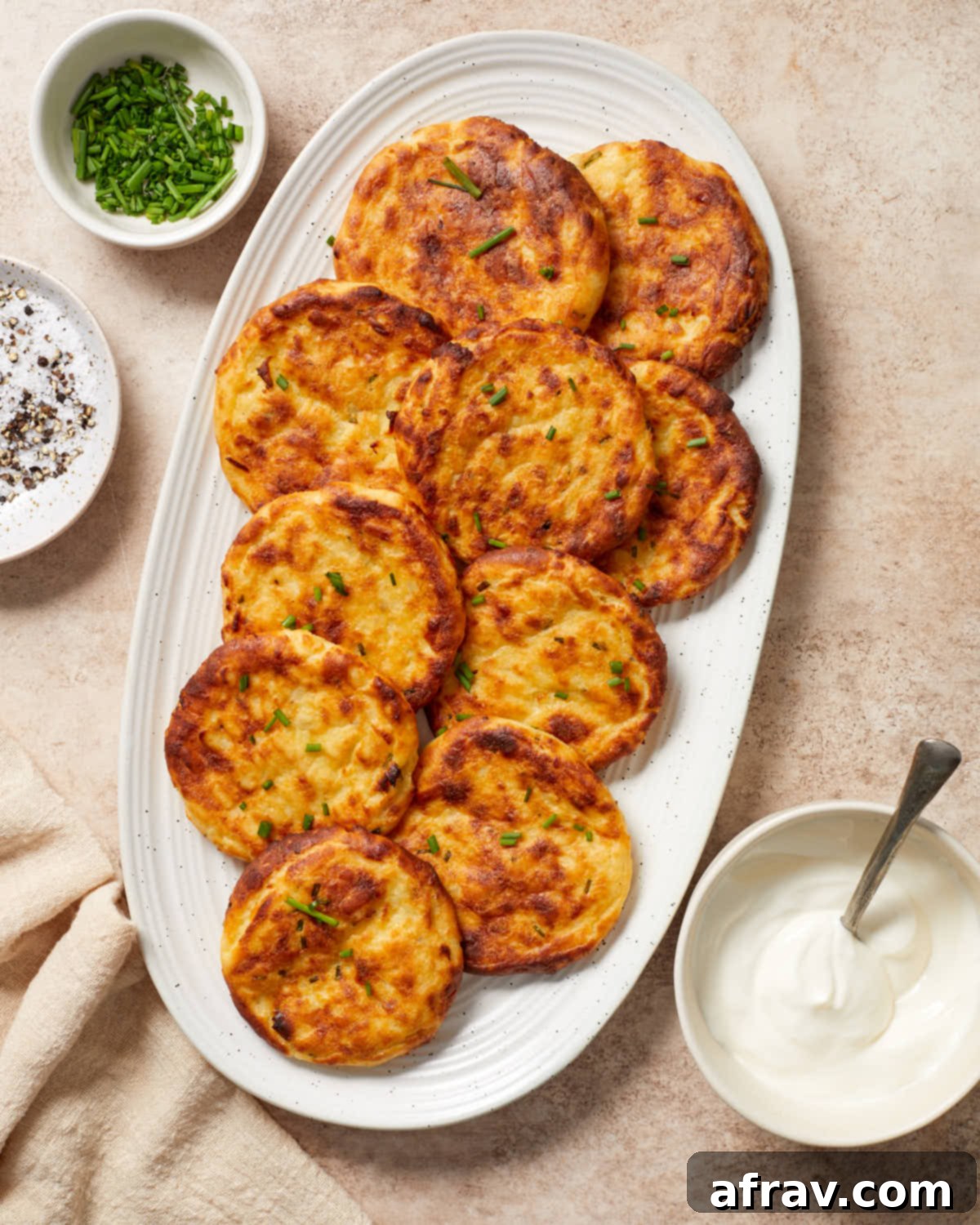 Golden brown and crispy potato cakes arranged beautifully on a white oval platter, ready to be served.