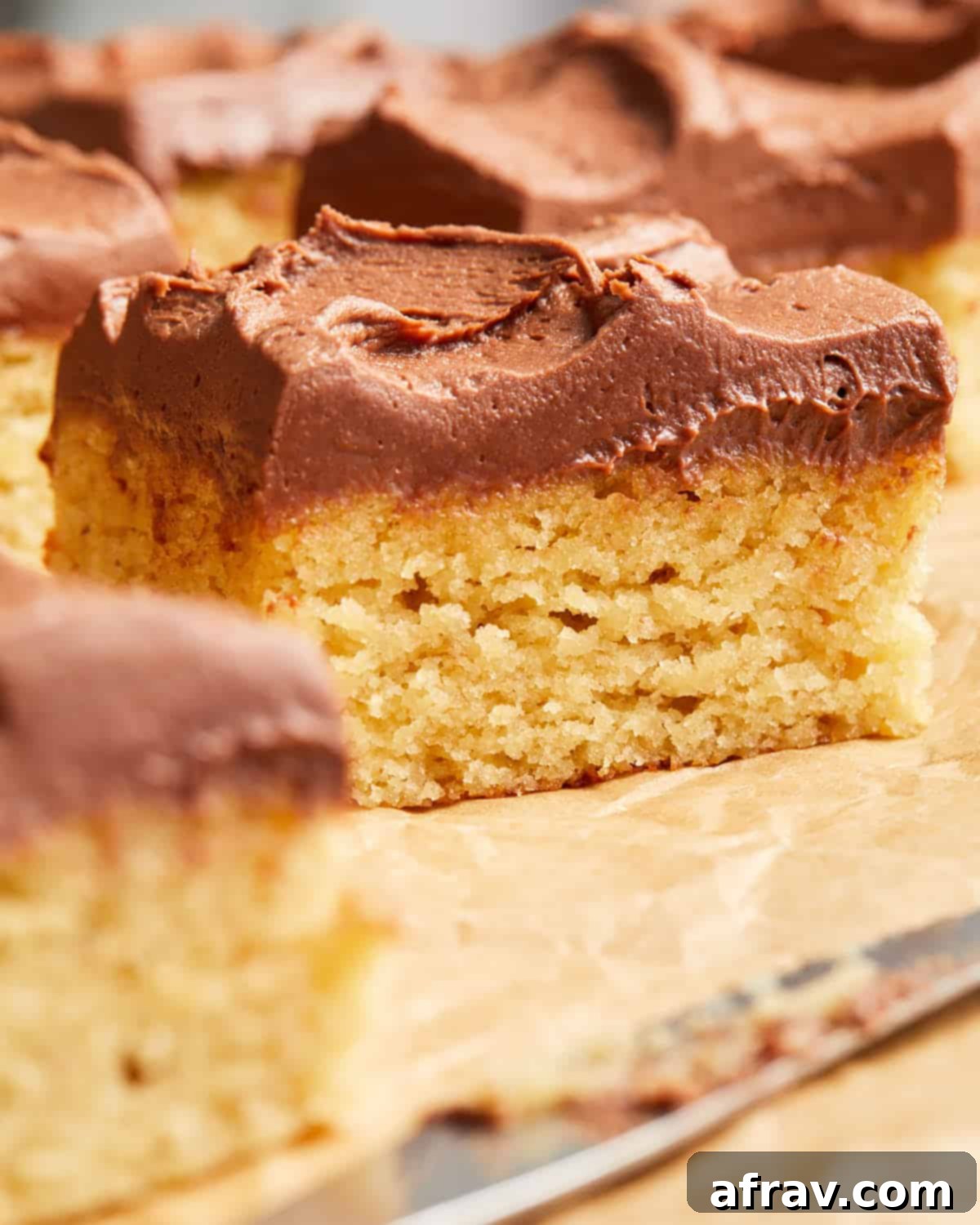 Up close view of a generous slice of almond flour banana cake with a thick layer of chocolate peanut butter frosting on top, presented on a white plate.