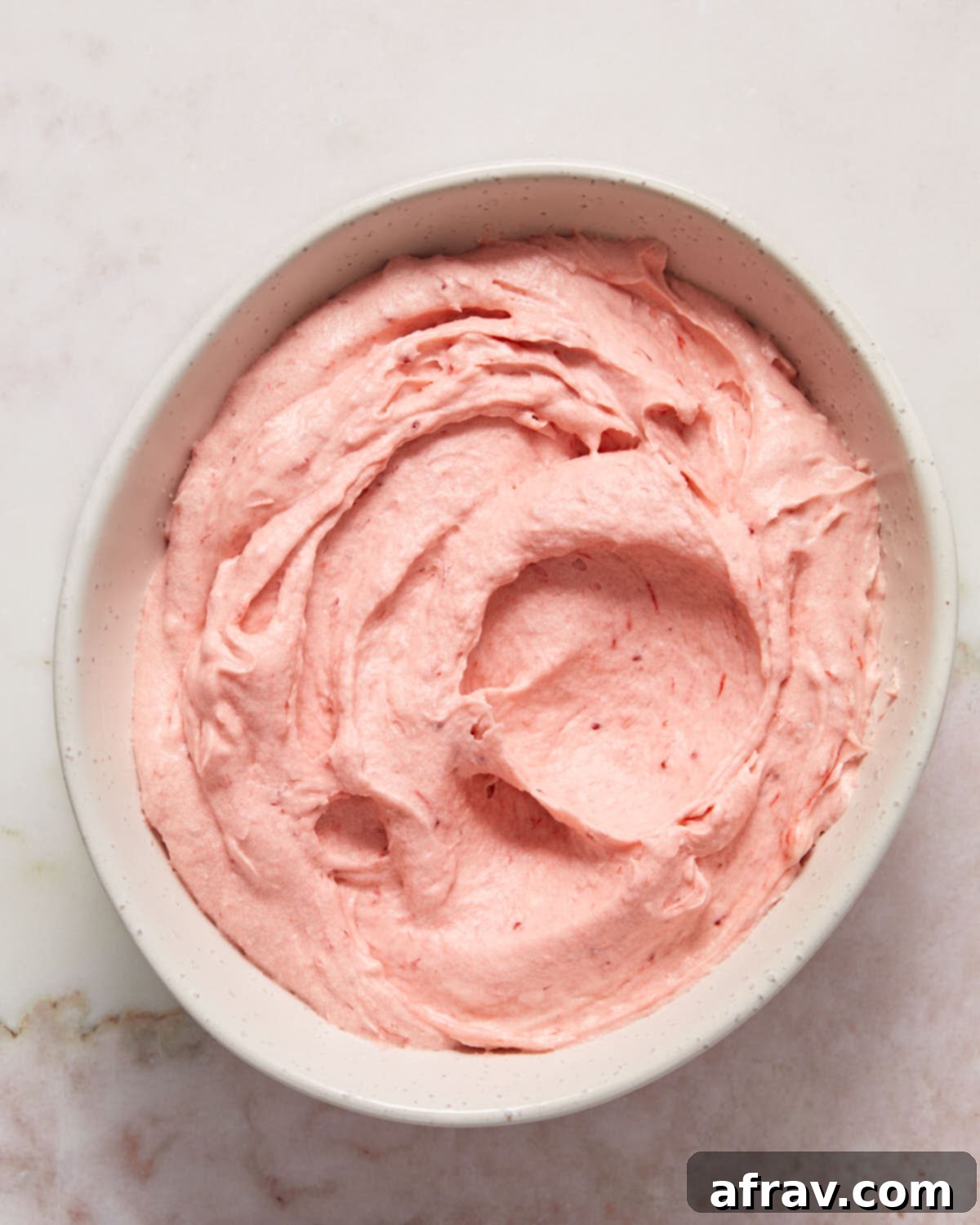 Close up view of strawberry buttercream in a white bowl.