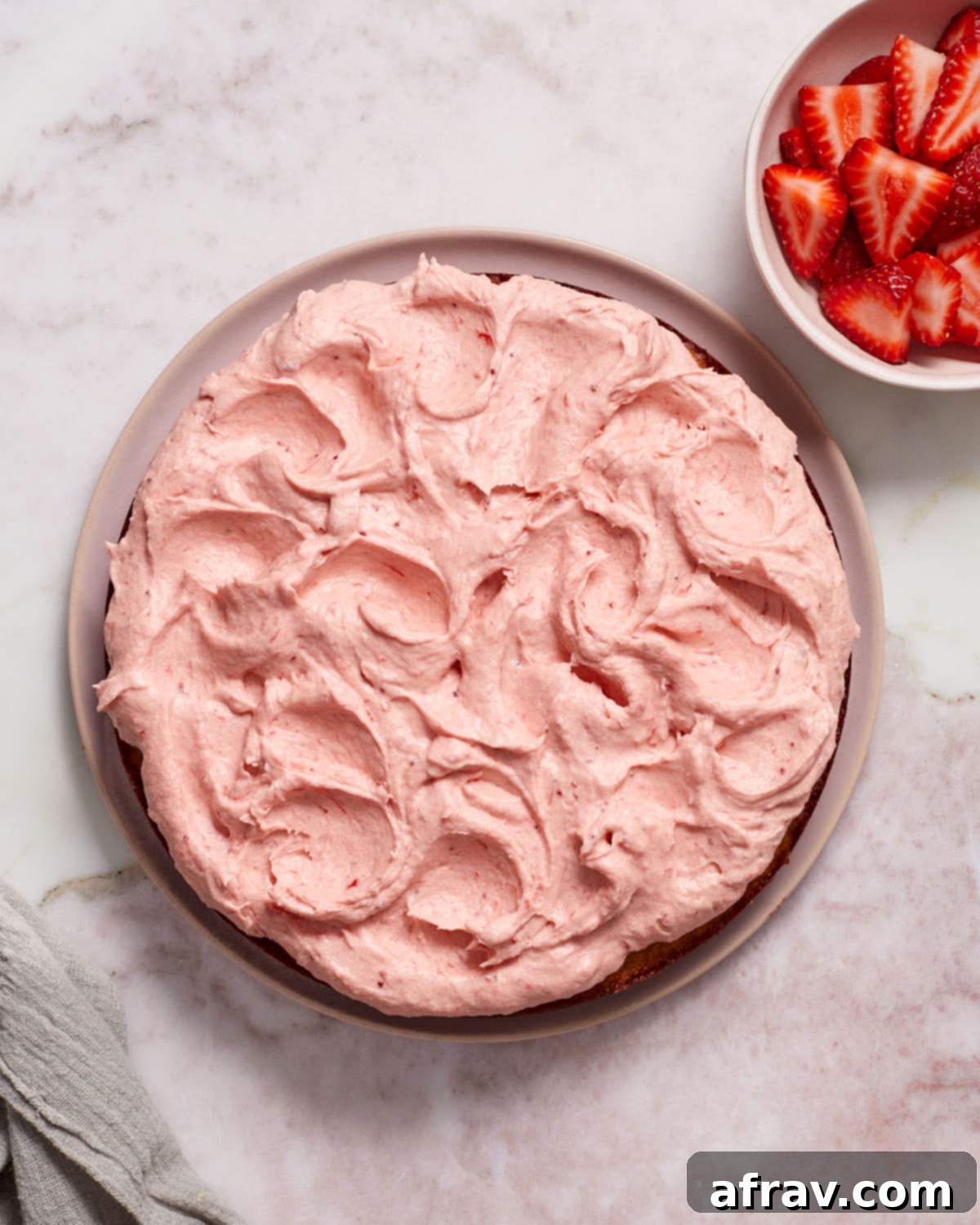 Overhead view of strawberry cake topped with strawberry frosting.