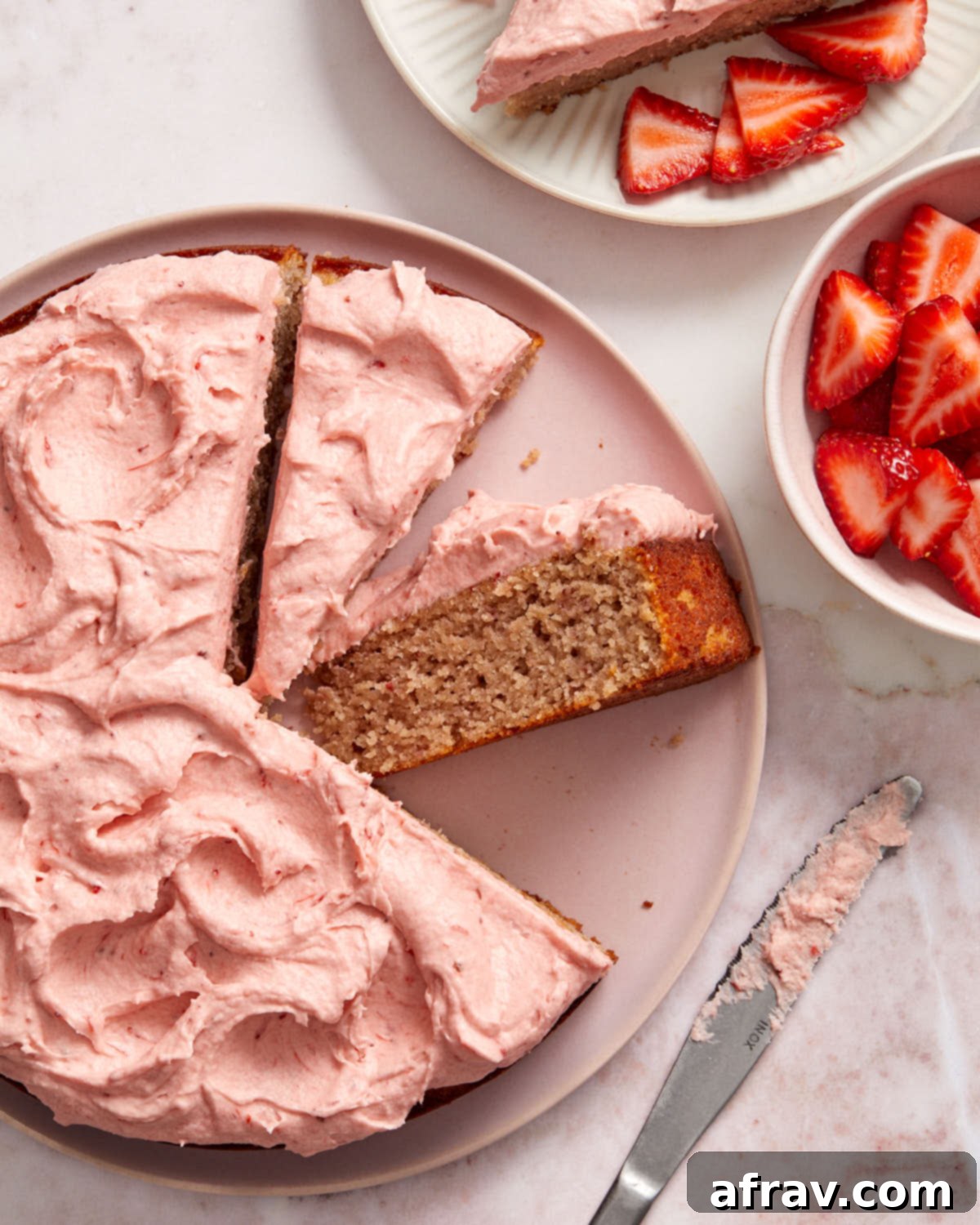 Strawberry cake sliced on a cake plate with a slice turned on its side to show the texture.