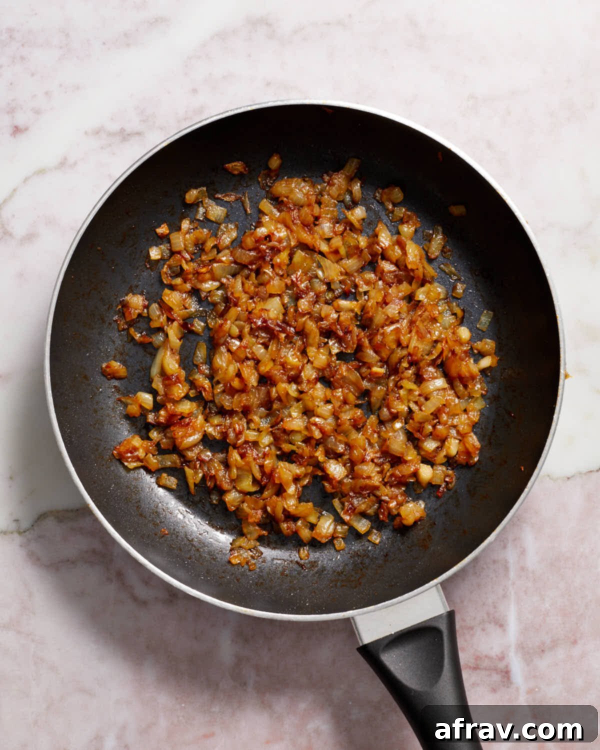 Beautifully golden-brown caramelized onions in a skillet, showcasing the result of slow cooking.