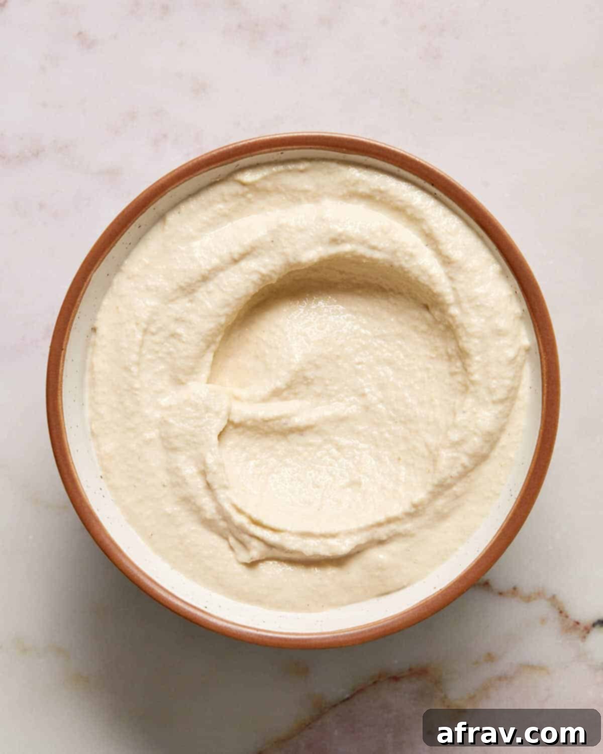 Smooth, creamy blended cashew mixture in a small white bowl, forming the dairy-free base of the dip.