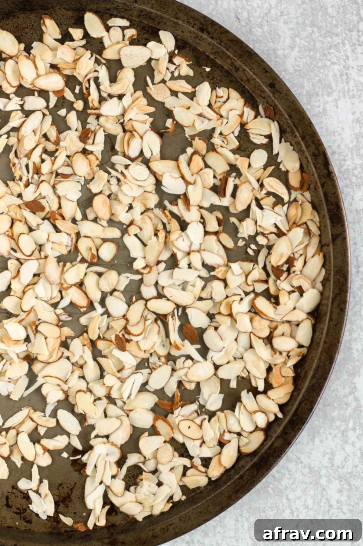 Toasted sliced almonds on a round baking sheet.