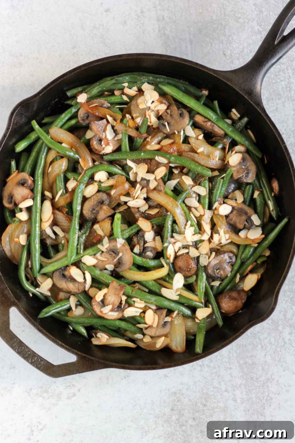 Savory Skillet Green Beans with Onions and Mushrooms 8 Green beans with onions, mushrooms, and sliced almonds in a cast iron skillet.