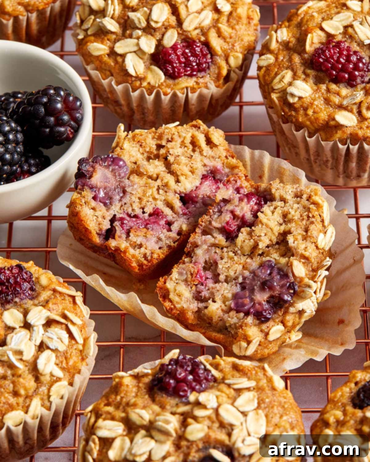 A banana blackberry oatmeal muffin cut open to reveal its moist, tender interior and generous pockets of juicy blackberries.