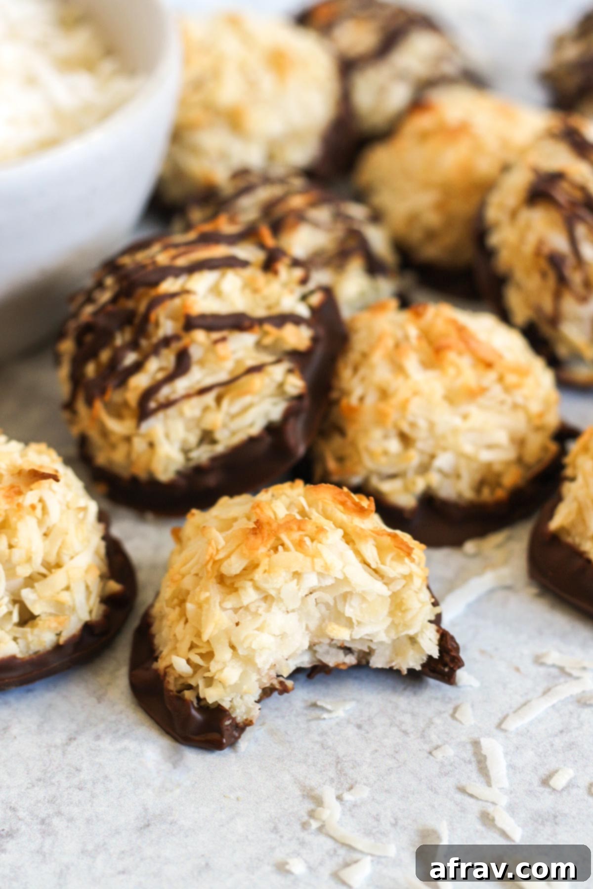 Coconut macaroon cookie with a bite taken out of it, with additional macaroons in the background.