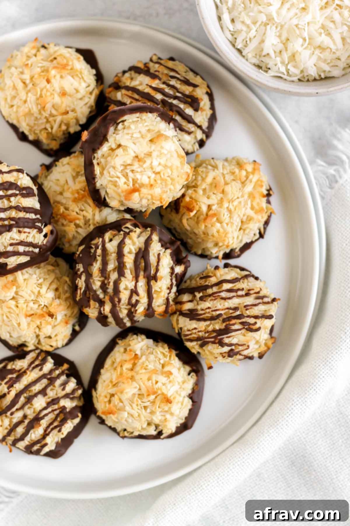 Coconut macaroons dipped in chocolate and some of them drizzled with chocolate on a plate.