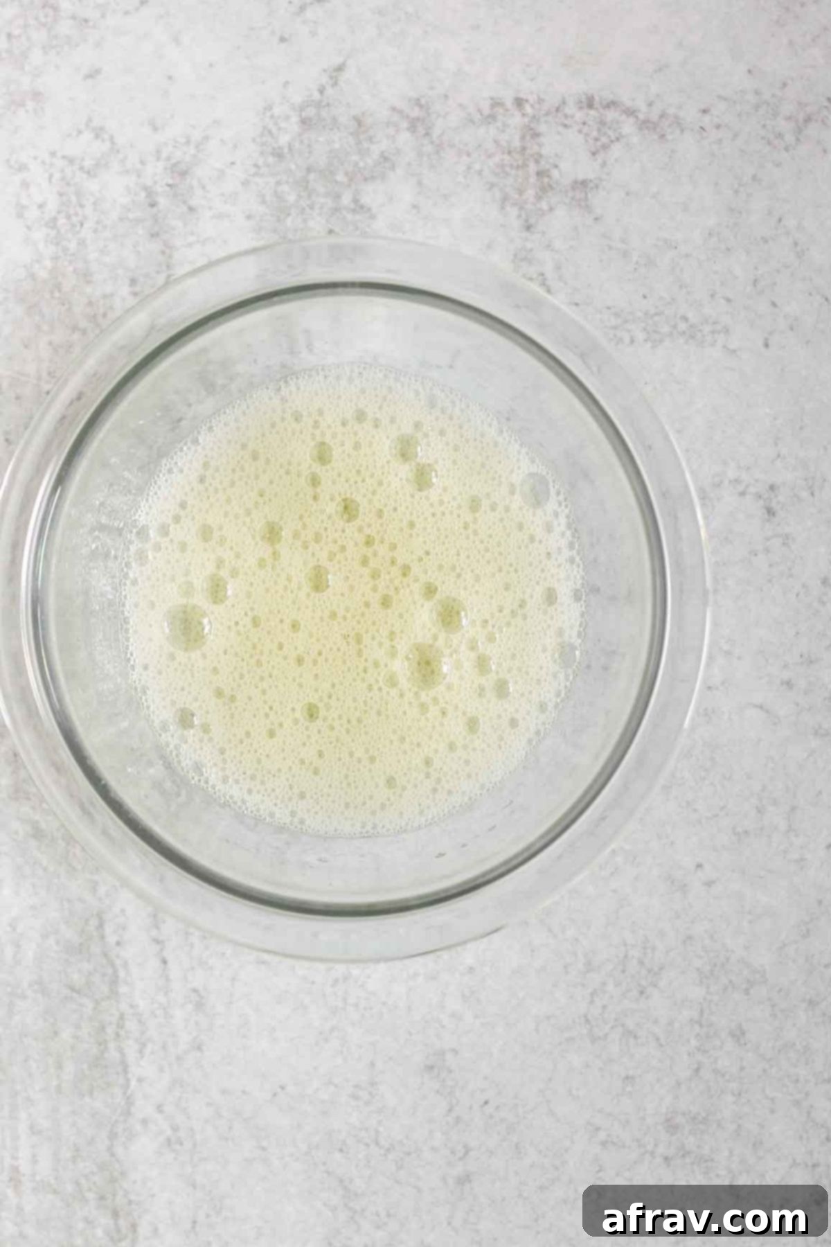Whisked egg whites in a small glass mixing bowl.
