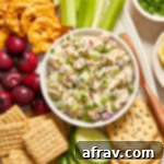 Tuna salad without mayo in a small bowl on a platter with crackers and veggies.
