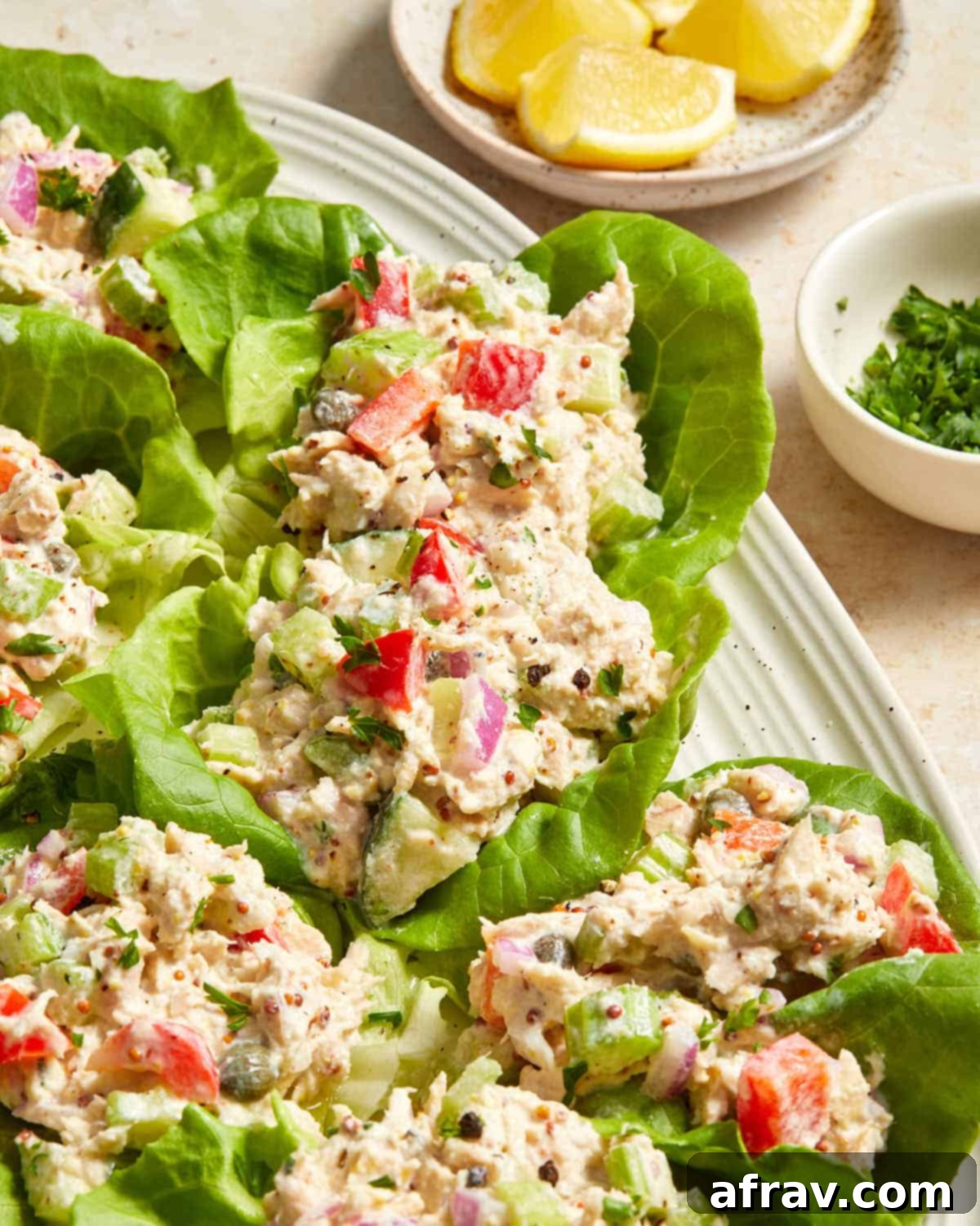 An angled view of several appetizing tuna lettuce wraps neatly arranged on a pristine white platter, highlighting their freshness and appeal.