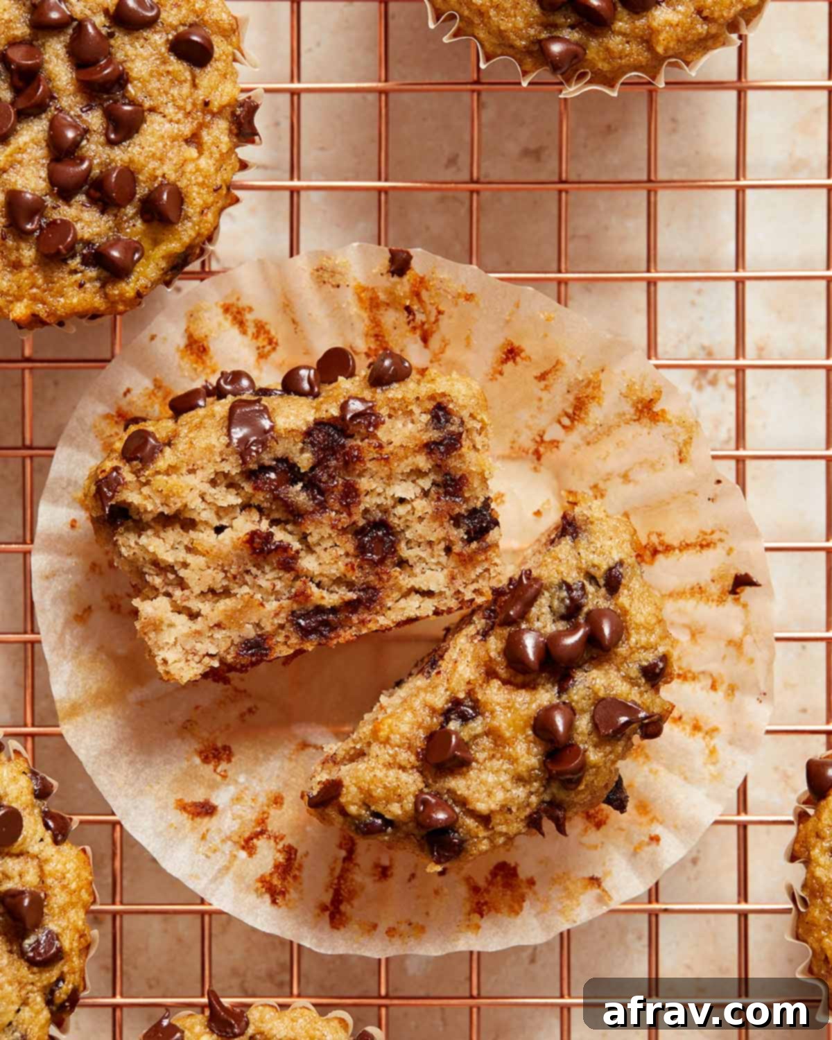 Irresistible Almond Flour Banana Muffins 2 Banana muffin cut in half on the muffin wrapper and showing the chocolate chips inside.
