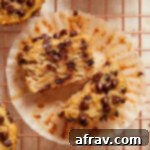 Irresistible Almond Flour Banana Muffins 8 An almond flour banana muffin cut in half and resting on the muffin wrapper on a wire cooling rack.