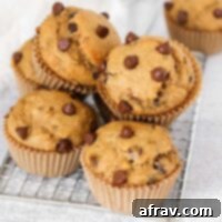 Stacked banana protein muffins with chocolate chips on a small rectangular wire cooling rack.