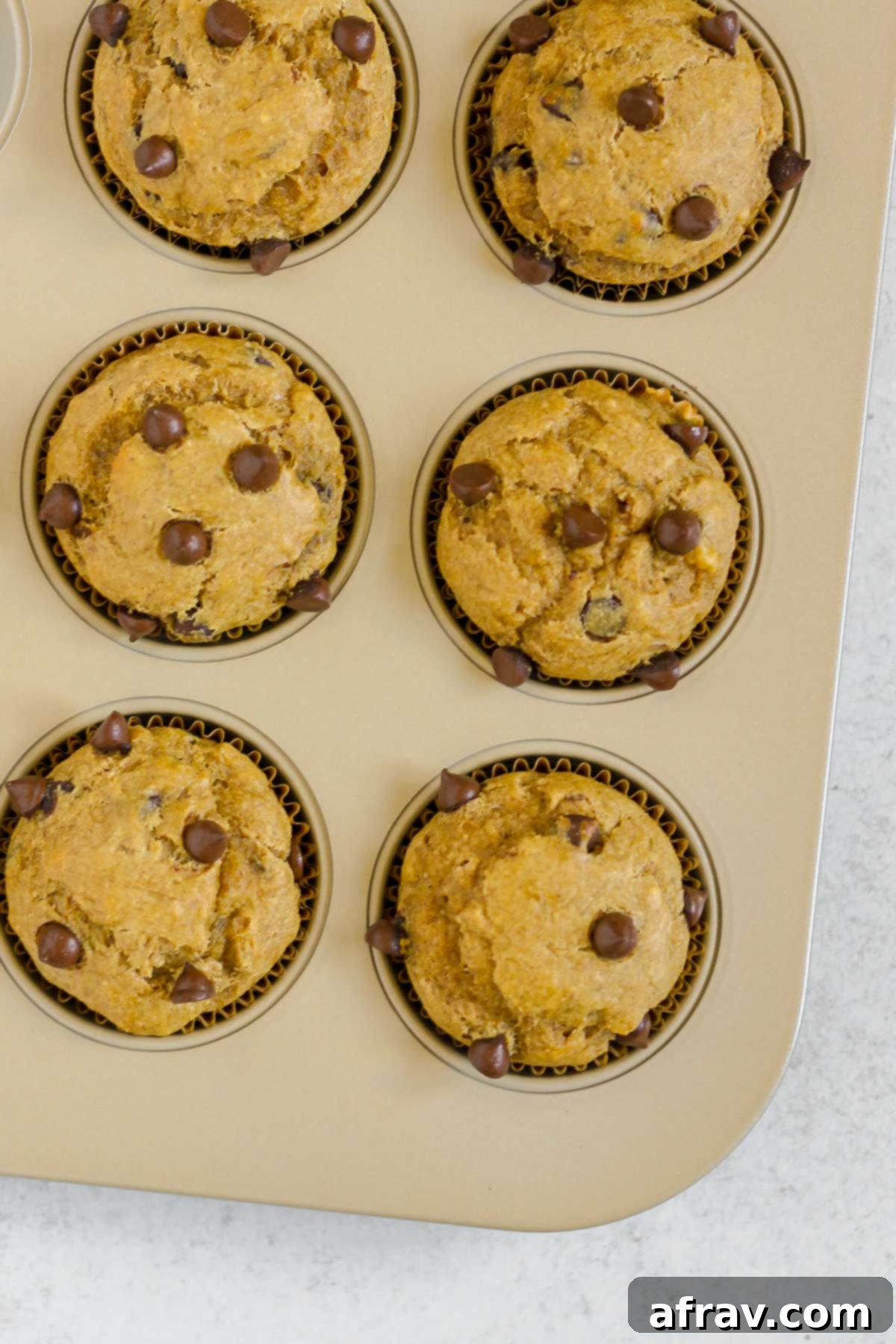 Freshly baked banana protein muffins cooling in a muffin tin, displaying their golden brown tops.