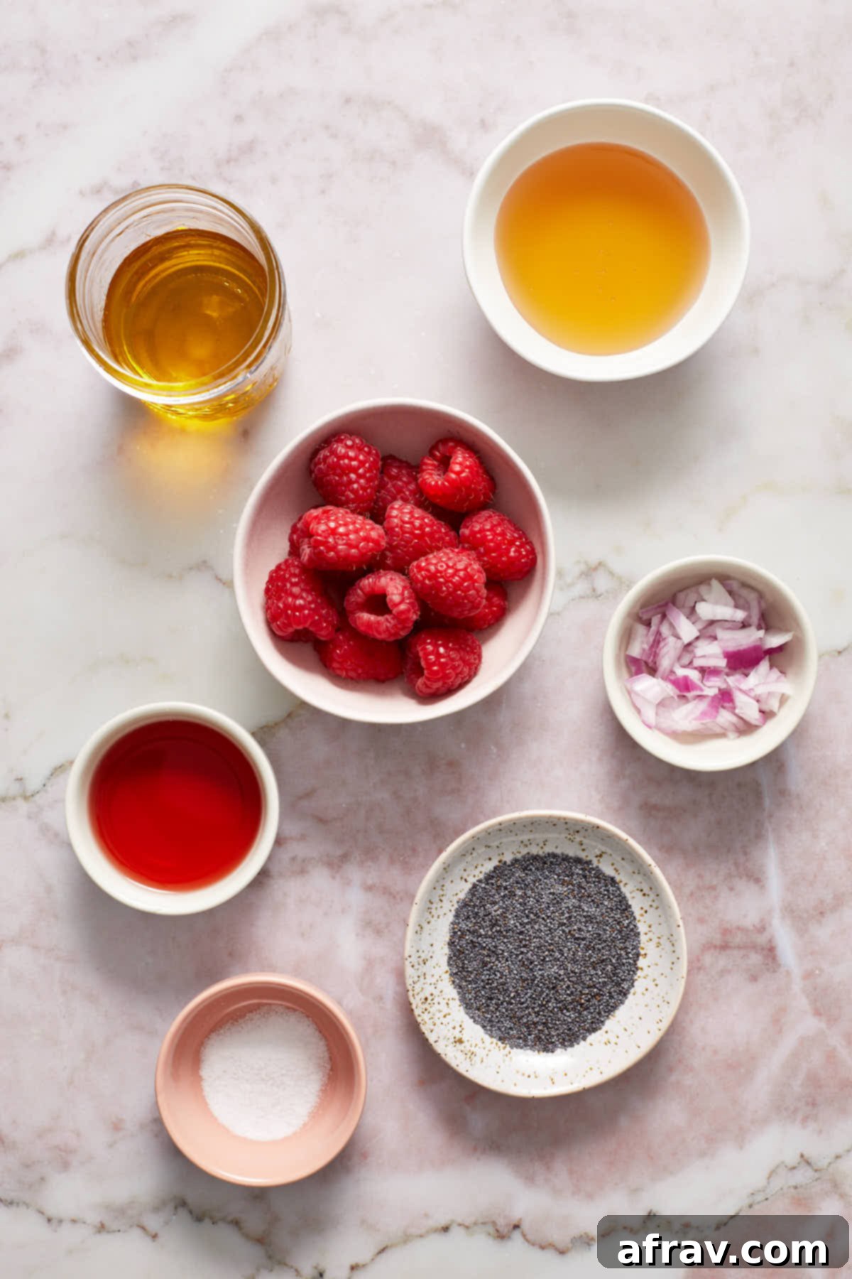 Individual dishes showcasing the key ingredients for raspberry poppy seed dressing: fresh raspberries, olive oil, honey, red wine vinegar, chopped red onion, salt, and poppy seeds.
