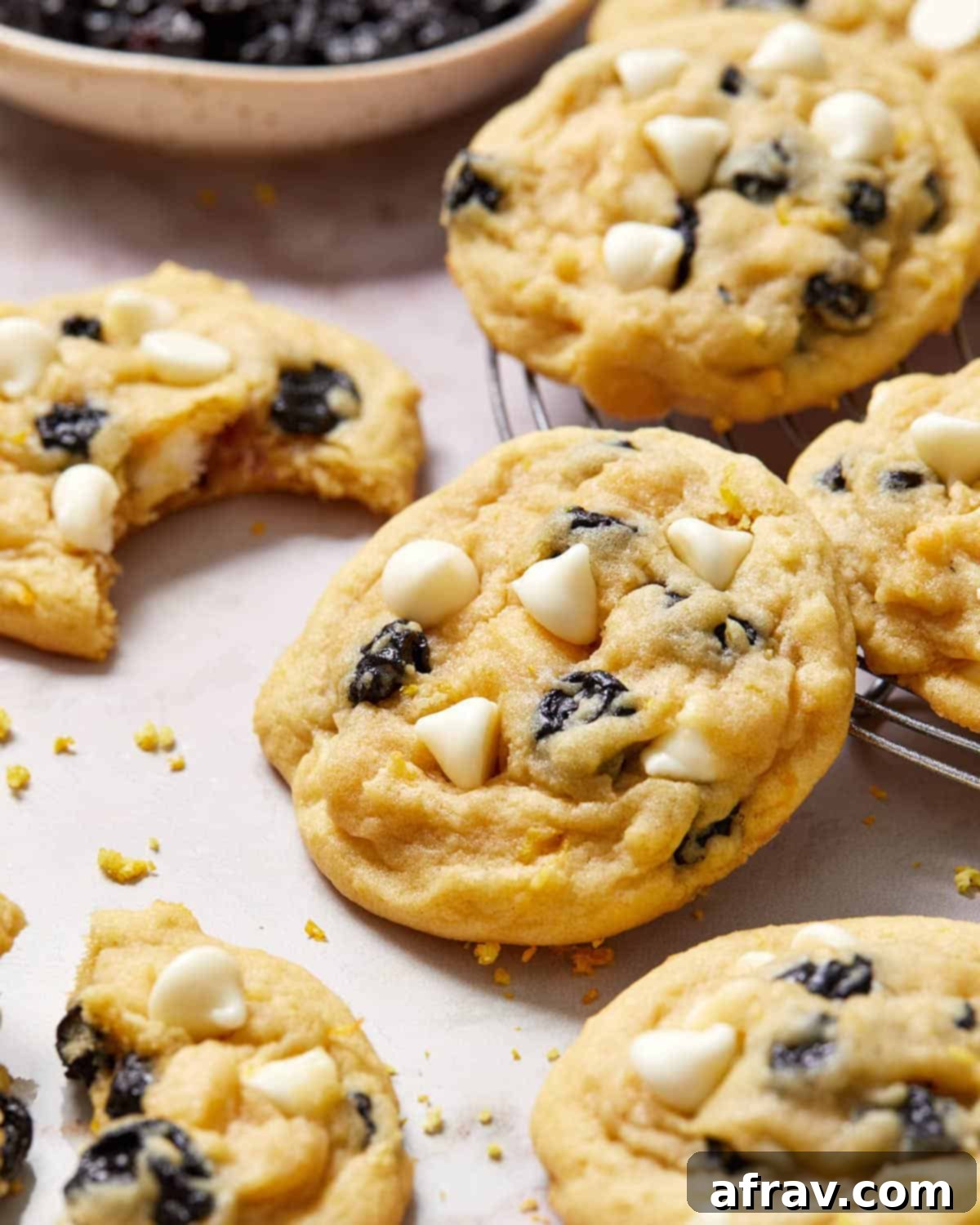 Close up view of a blueberry lemon cookie propped up on a cooling rack, showcasing its soft texture and blueberry distribution.