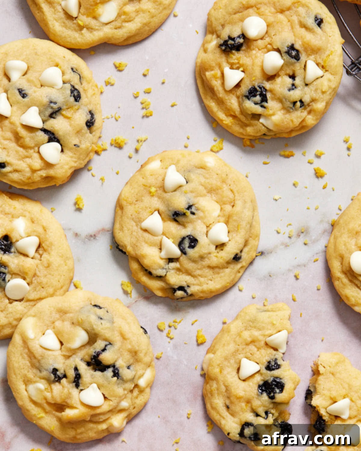 A display of blueberry lemon cookies artfully arranged on a light surface, with lemon zest lightly sprinkled around for garnish.