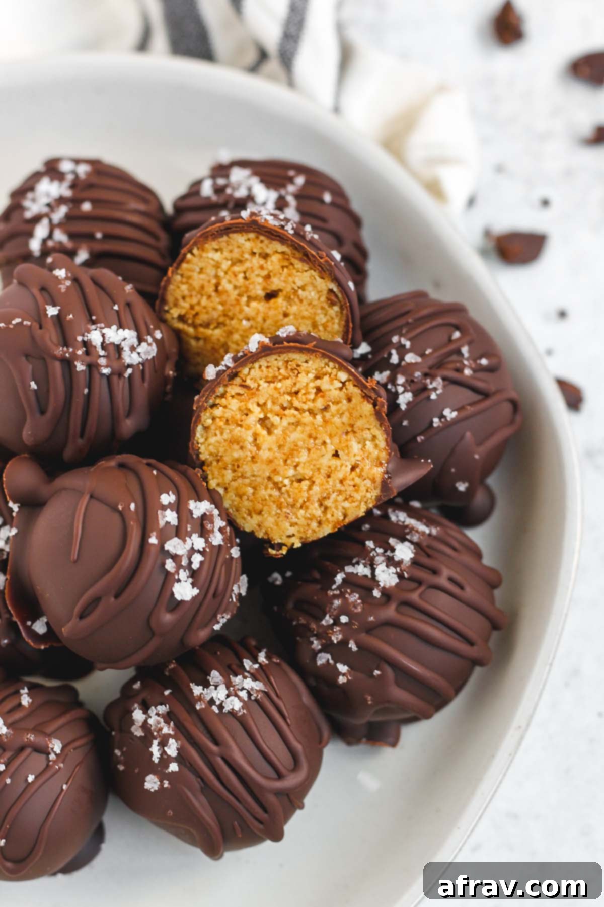Stacked healthy chocolate covered peanut butter balls with one cut open to reveal the creamy peanut butter center.