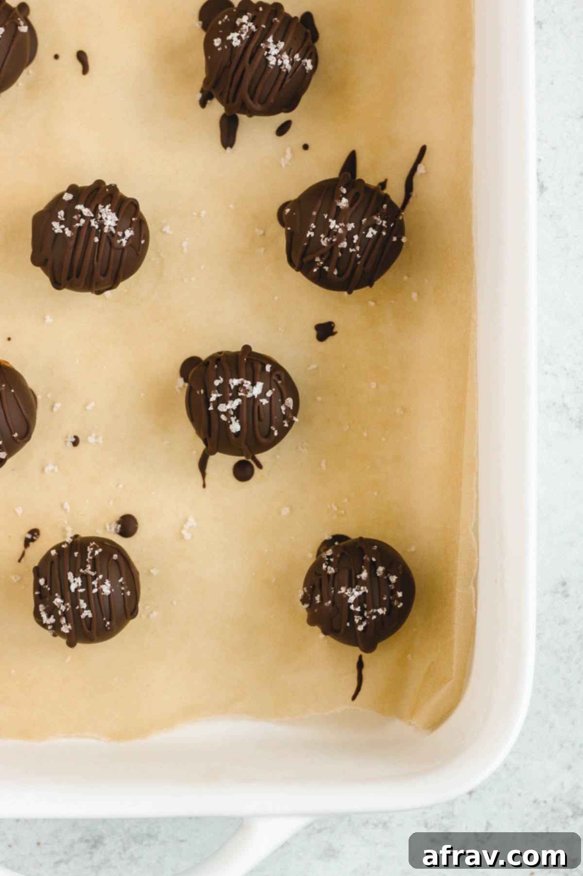 Close-up of freshly chocolate covered peanut butter balls, elegantly drizzled with extra chocolate and sprinkled with coarse sea salt.