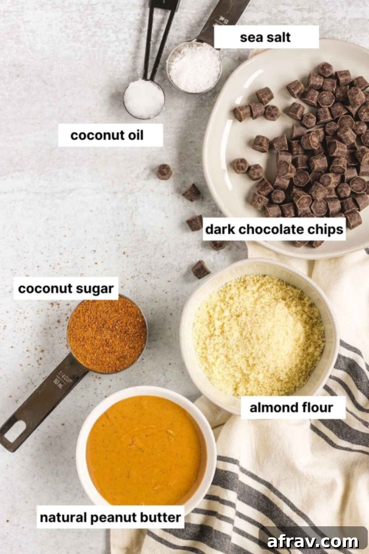 Labeled wholesome ingredients laid out for making chocolate covered peanut butter balls: natural peanut butter, almond flour, coconut sugar, dark chocolate chips, coconut oil, and sea salt.