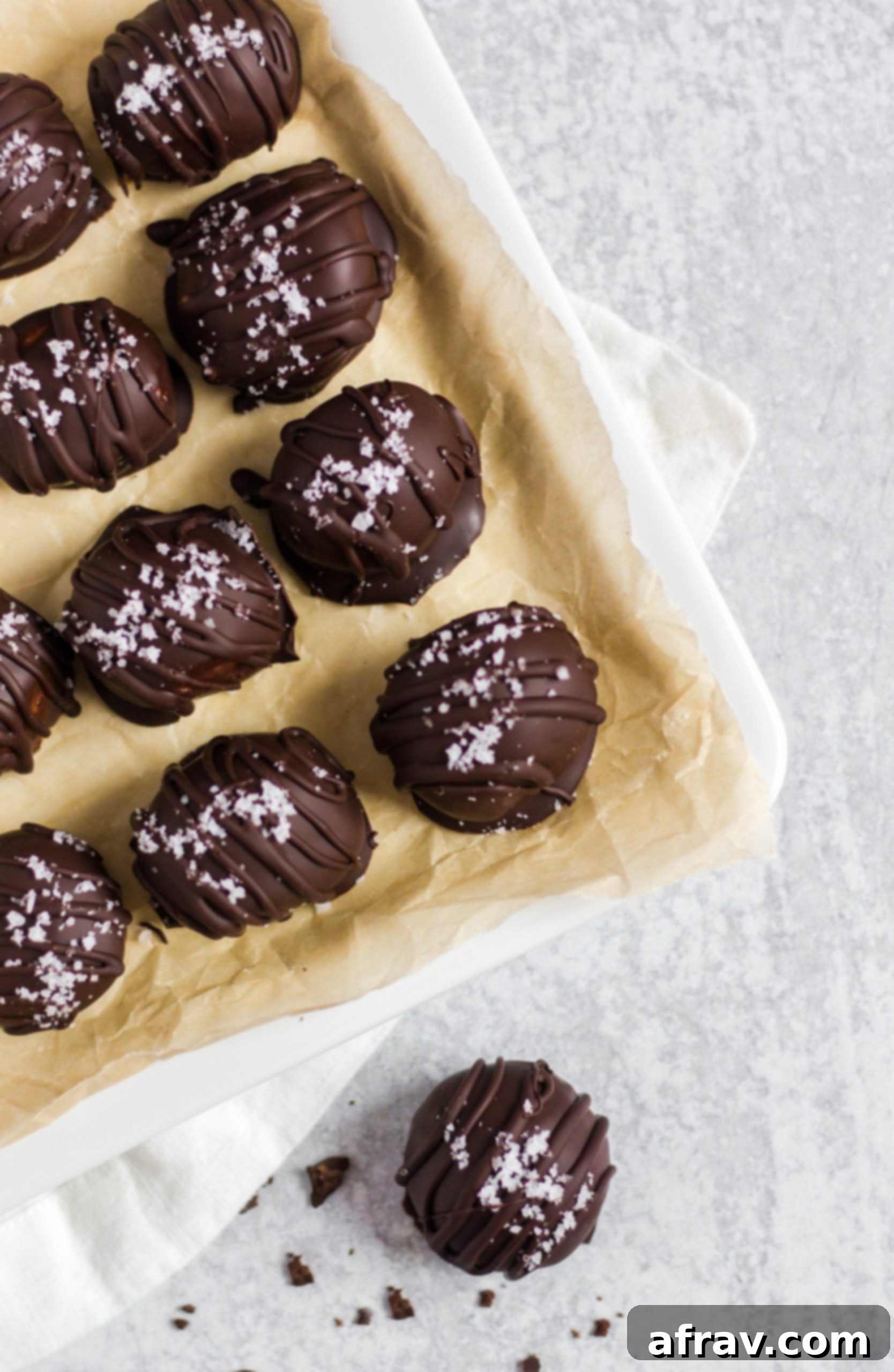 Overhead view of several chocolate covered peanut butter balls arranged on a white serving tray.