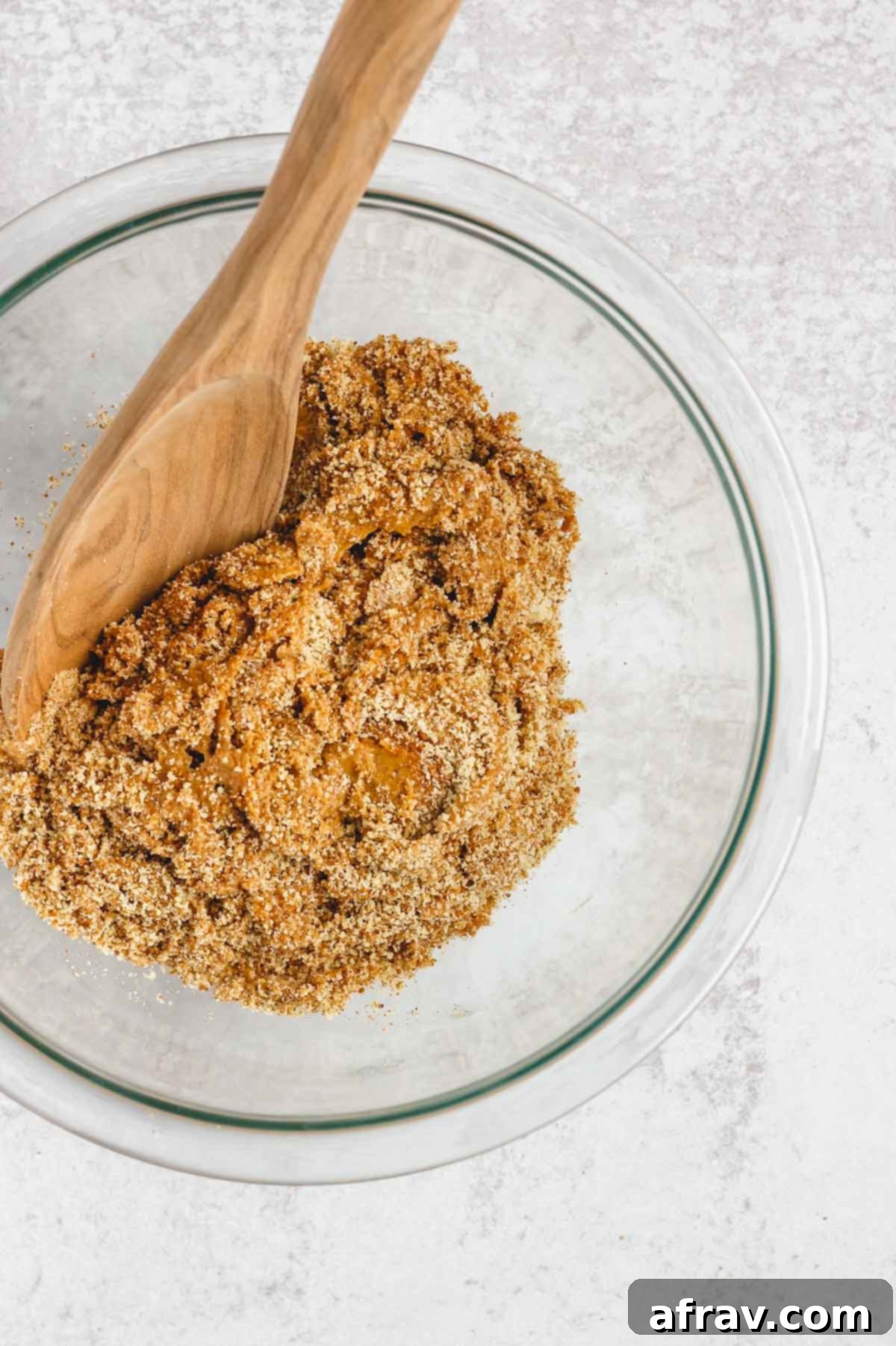 Ingredients for peanut butter dough being mixed together in a clear glass bowl.
