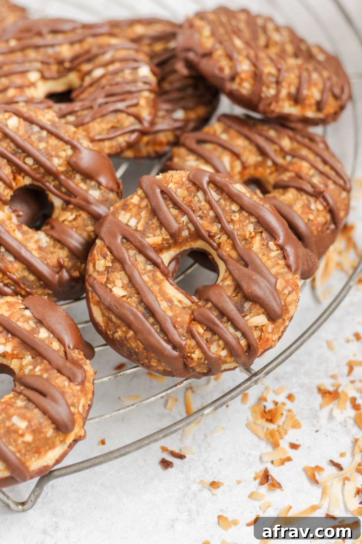 A stack of three homemade Samoa cookies resting on a round wire cooling rack, showcasing their layered texture and chocolate drizzle.