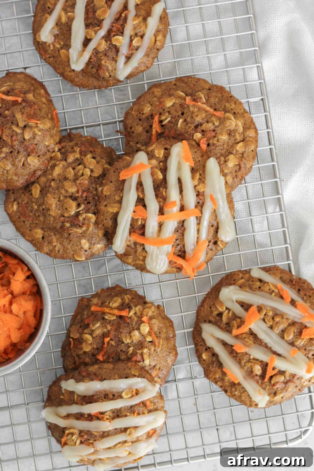Spiced Carrot Oatmeal Delights 11 Carrot cake oatmeal cookies, some with a glaze on the top, on a rectangular wire cooling rack.