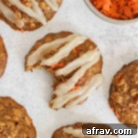 Spiced Carrot Oatmeal Delights 12 Carrot cake oatmeal cookie with coconut butter frosting in a zig zag pattern on the top.