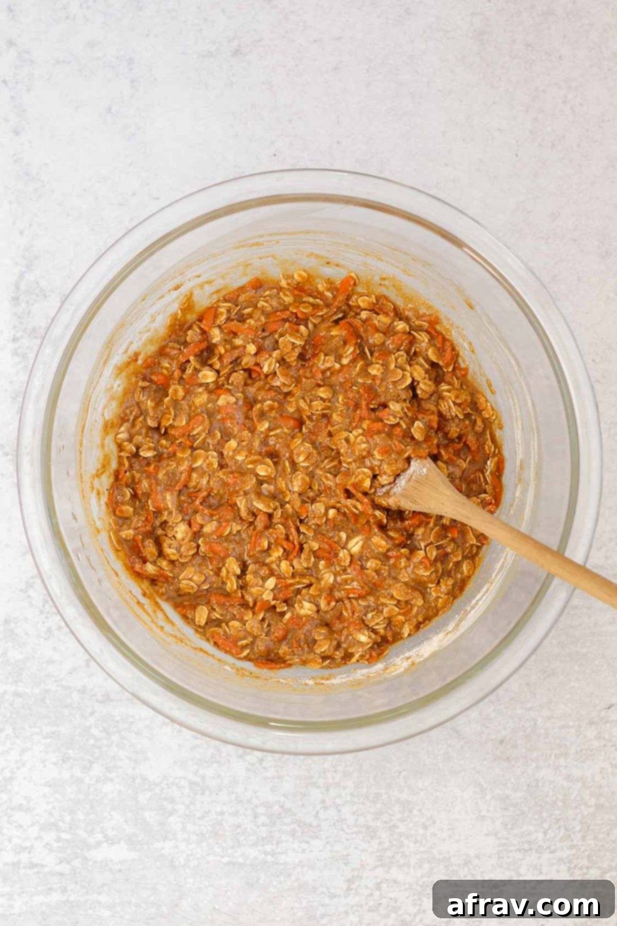 Spiced Carrot Oatmeal Delights 6 Carrot cake oatmeal cookie dough mixed in a glass mixing bowl with a wooden spoon.