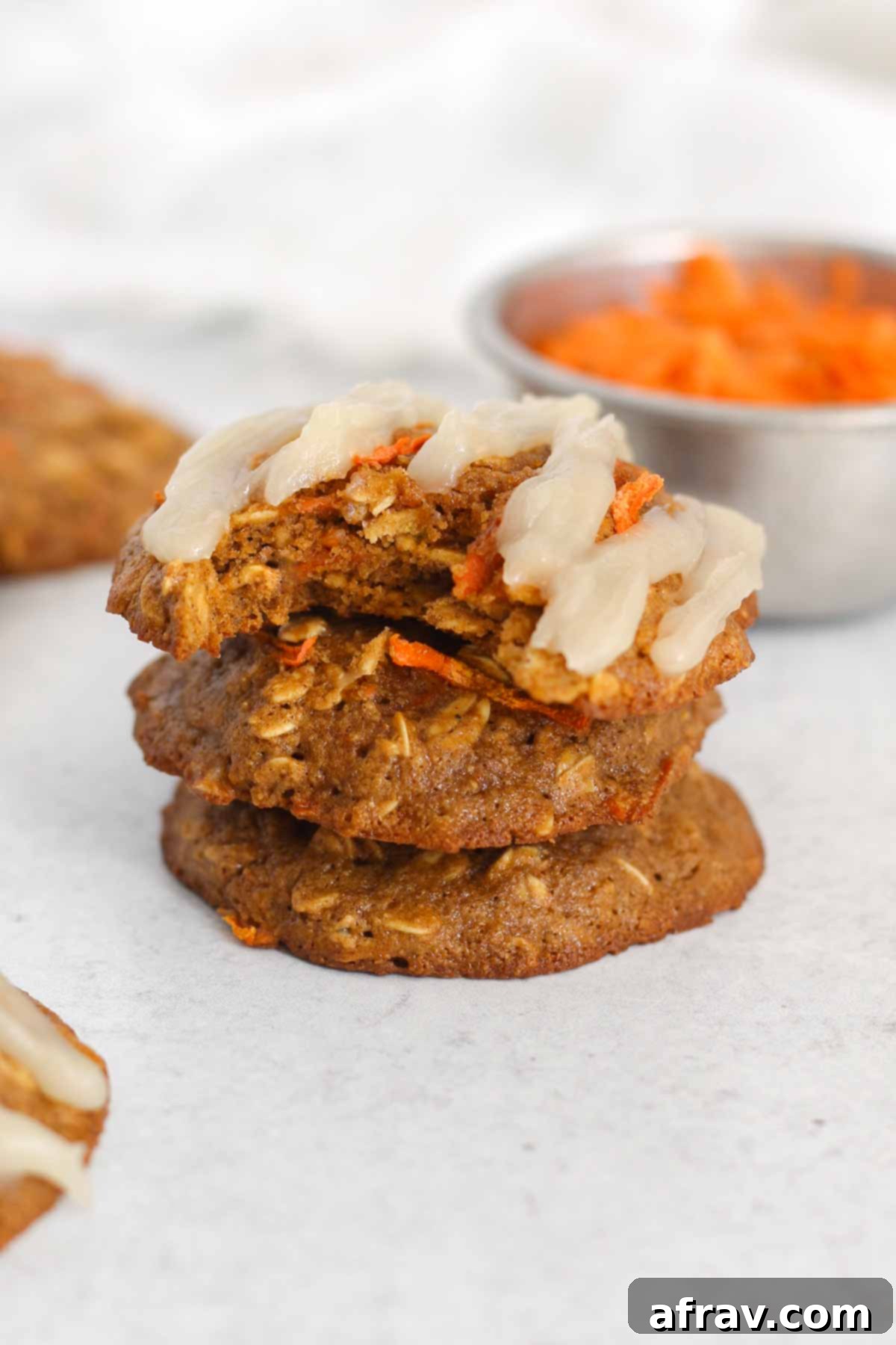 Spiced Carrot Oatmeal Delights 10 Oatmeal carrot cake cookies stacked 3 high with a bit taken from the top one to show texture.