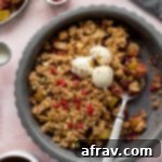 Wholesome Vegan Gluten-Free Apple Cranberry Crisp 2 Apple cranberry crisp in a grey pie plate with scoops of crisp taken out and a cup of coffee off to the side.