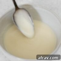 Coconut butter glaze dripping from a spoon in a small ceramic bowl.