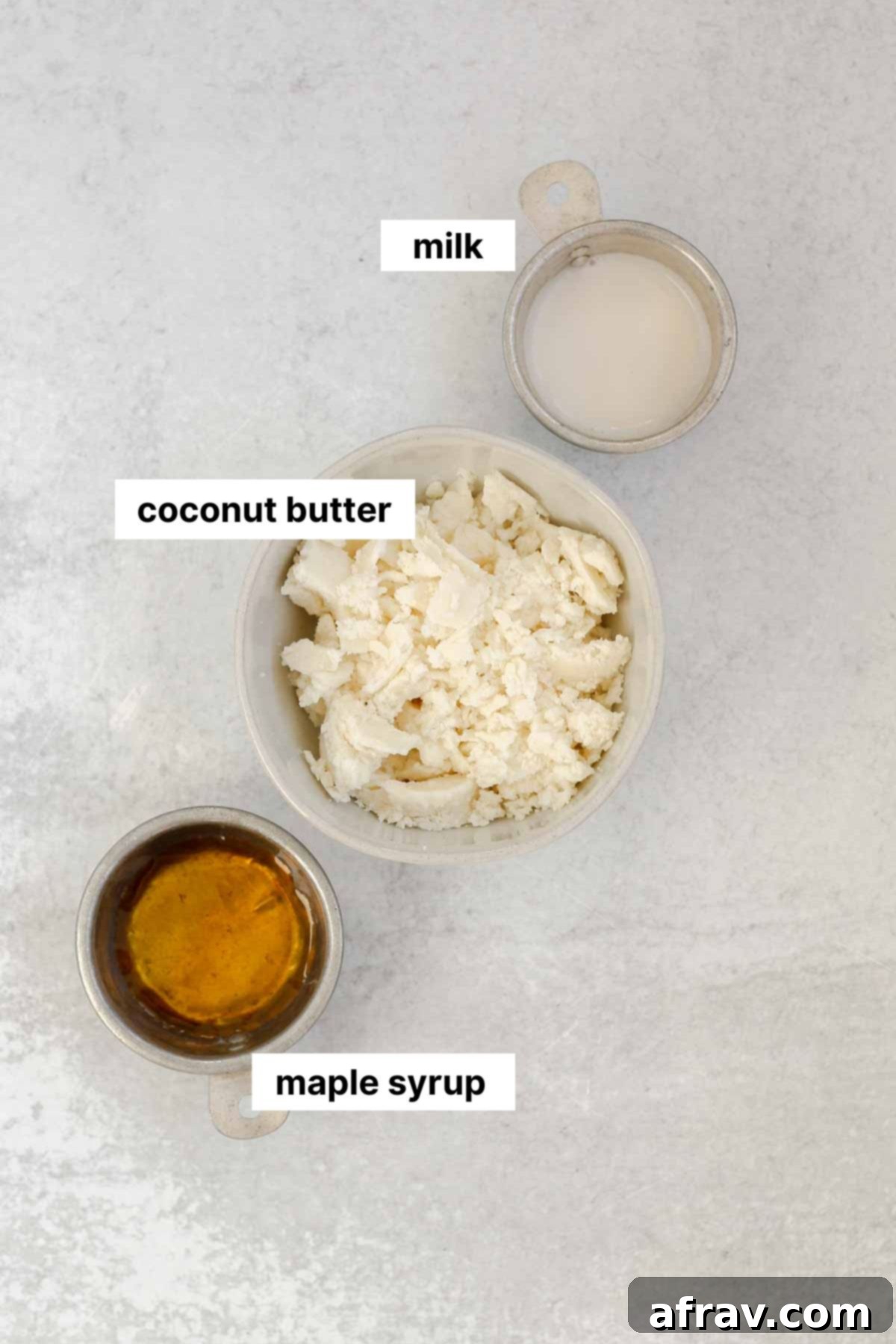 Three essential ingredients for coconut butter glaze: a jar of coconut butter, a bottle of maple syrup, and a carton of almond milk, neatly arranged on a light surface.