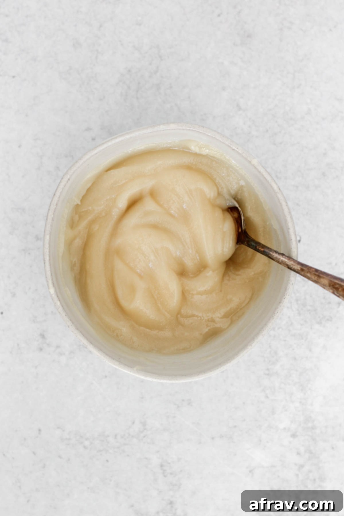 Melted coconut butter mixed with golden maple syrup in a bowl, appearing thick.