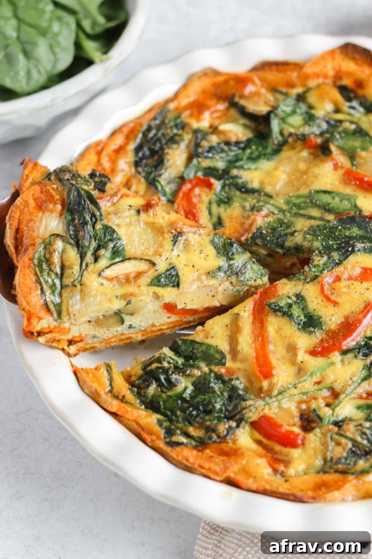 A serving of sweet potato crust quiche being carefully lifted from the pie dish with a pie server, showcasing its perfect slice and firm crust.