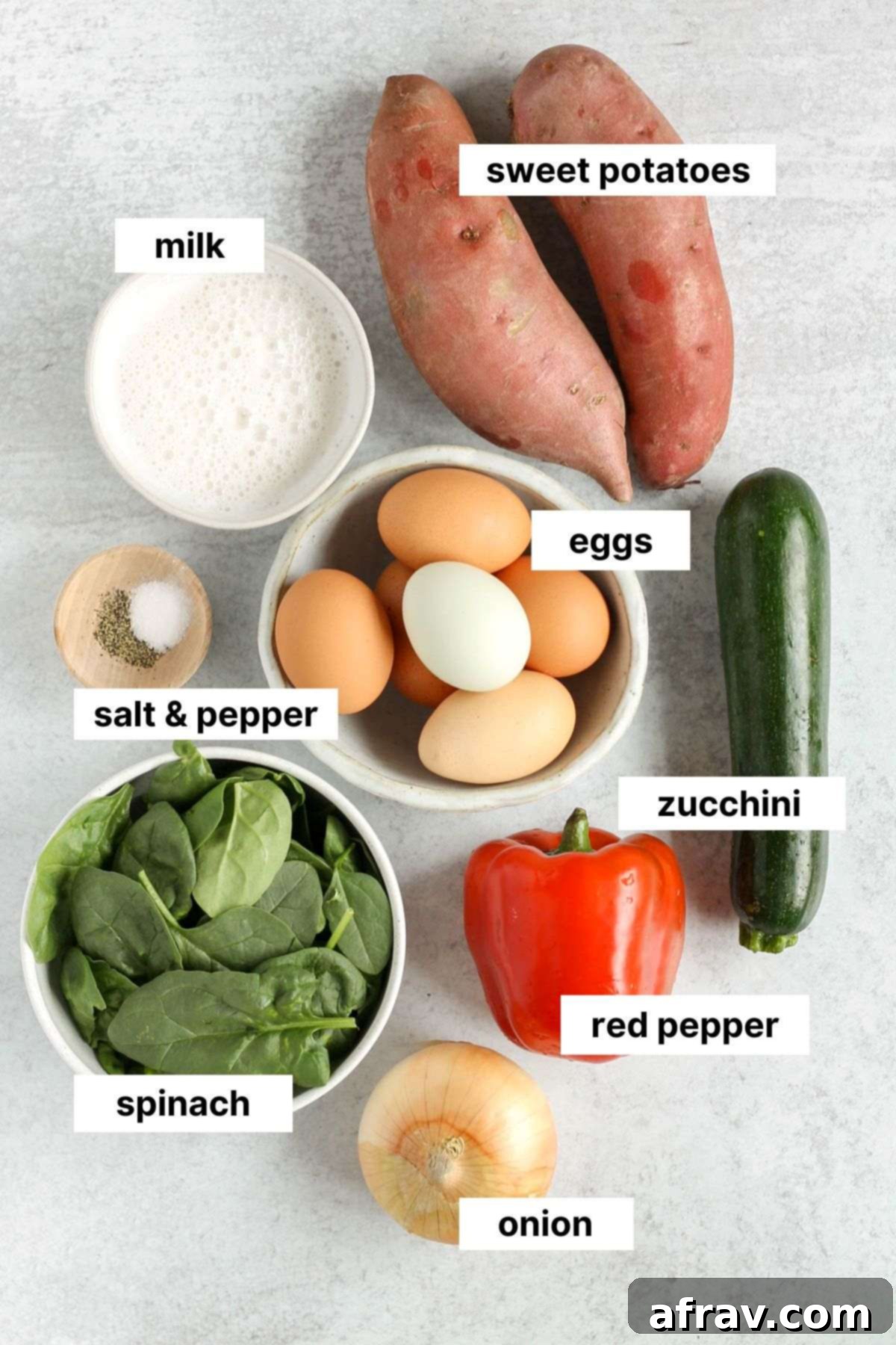 Labeled ingredients for sweet potato crust quiche laid out on a kitchen counter, including eggs, milk, sweet potatoes, and various fresh vegetables.