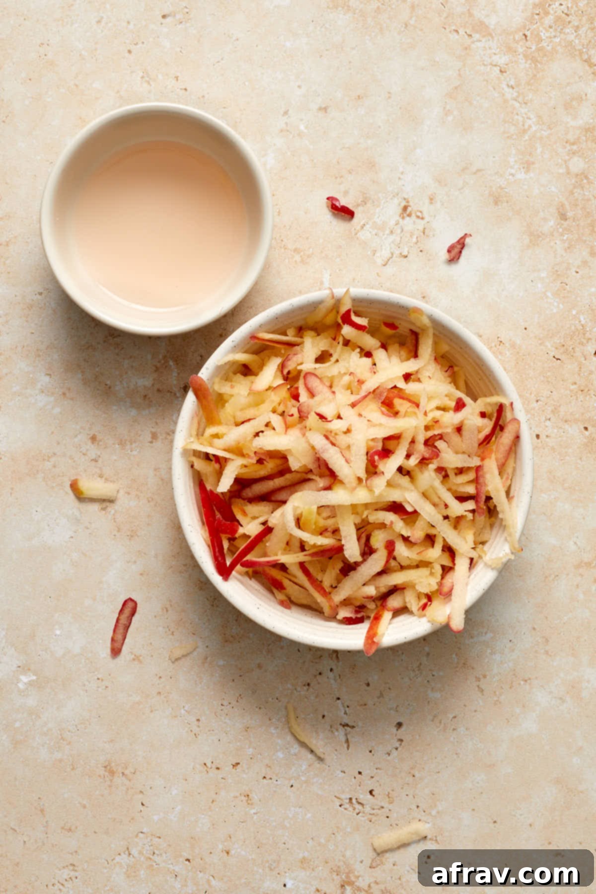Delightful Almond Apple Cake 5 Grated apple in a small dish with apple juice squeezed out in a side dish.