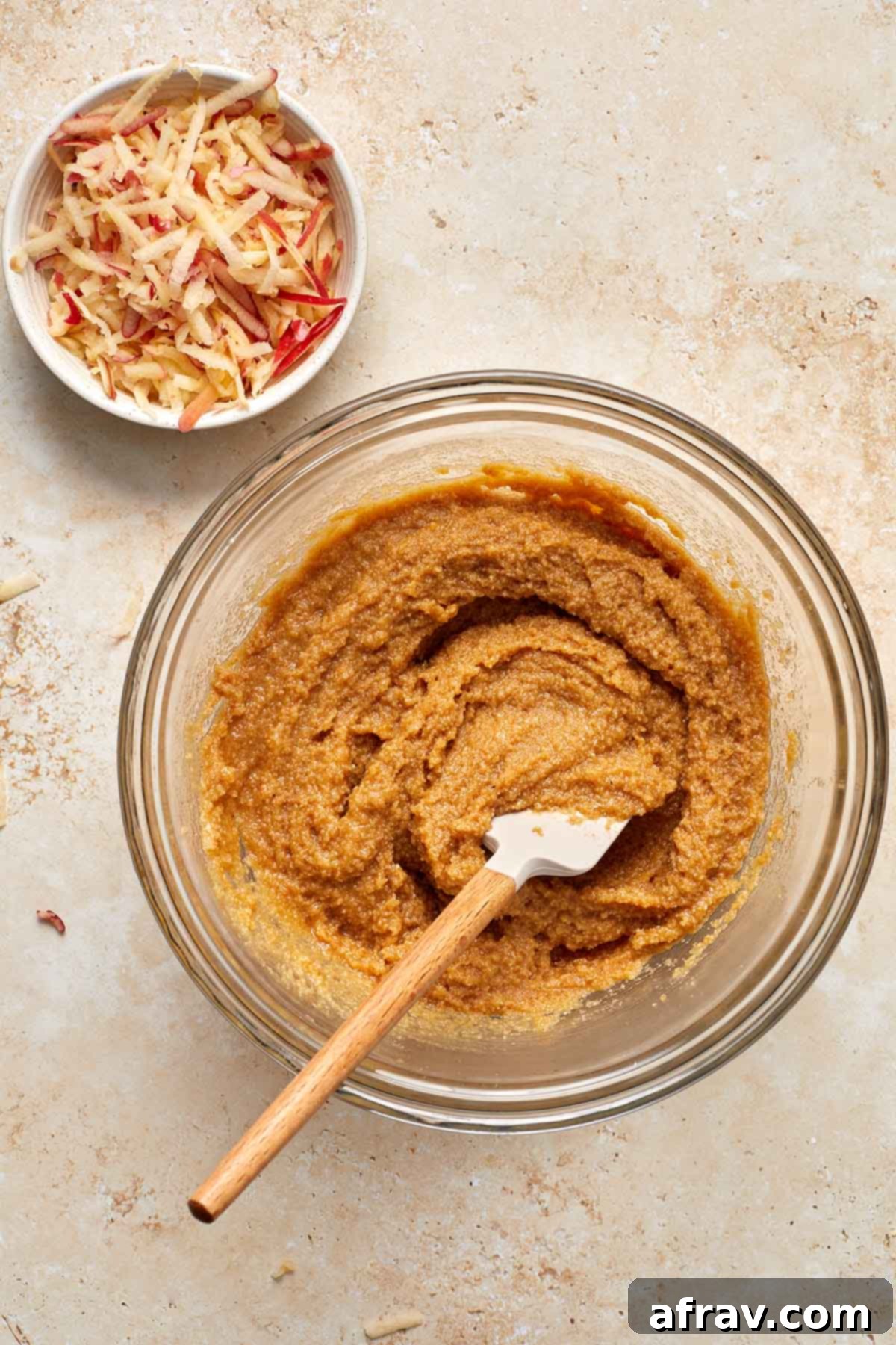 Delightful Almond Apple Cake 8 Cake batter mixed together in a glass bowl with shredded apple on the side.