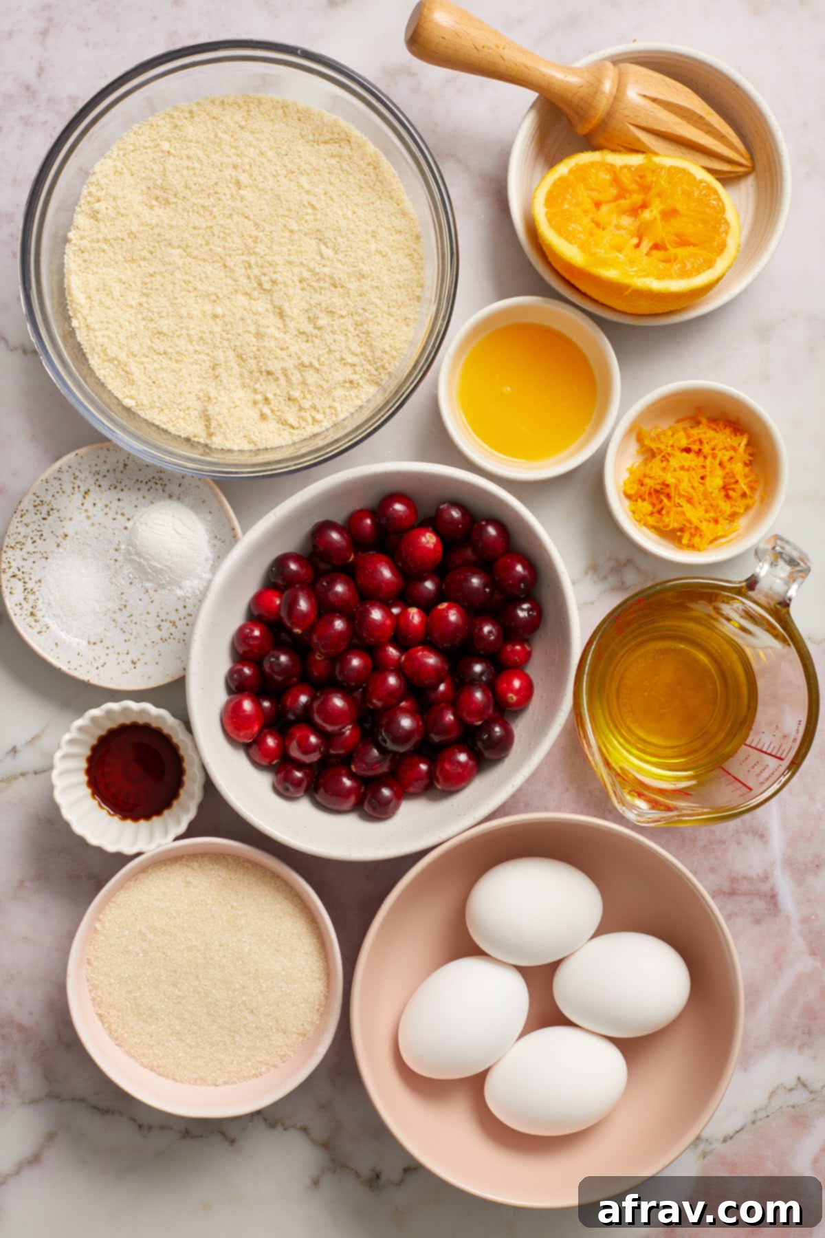 Ingredients for almond flour cranberry orange bread arranged neatly in individual bowls on a white surface.