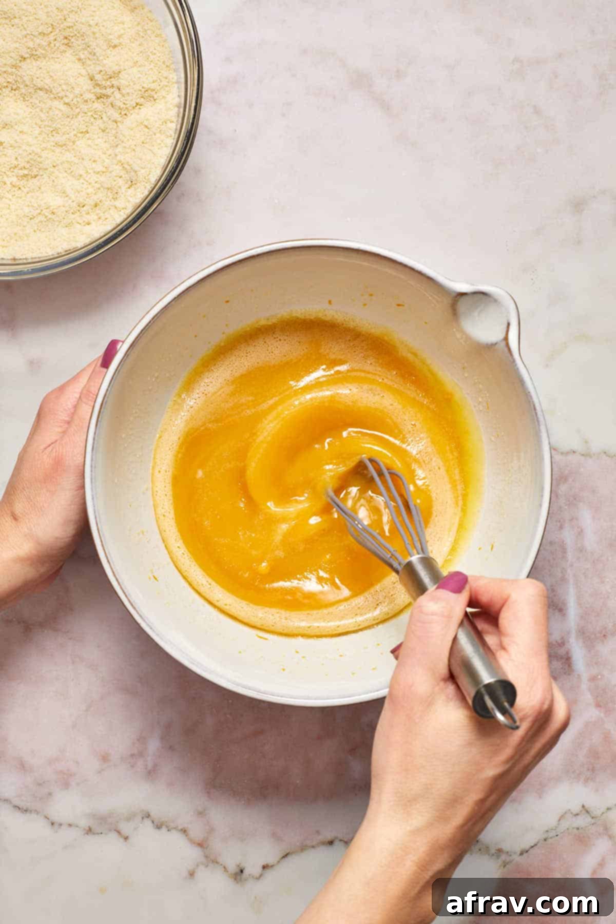 Wet ingredients, including eggs, sugar, oil, orange zest, juice, and vanilla, being whisked together in a separate large bowl.