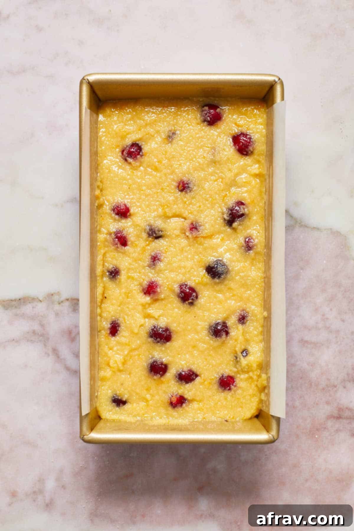 Overhead view of the smooth cranberry orange bread batter poured into a prepared loaf pan, ready for baking.