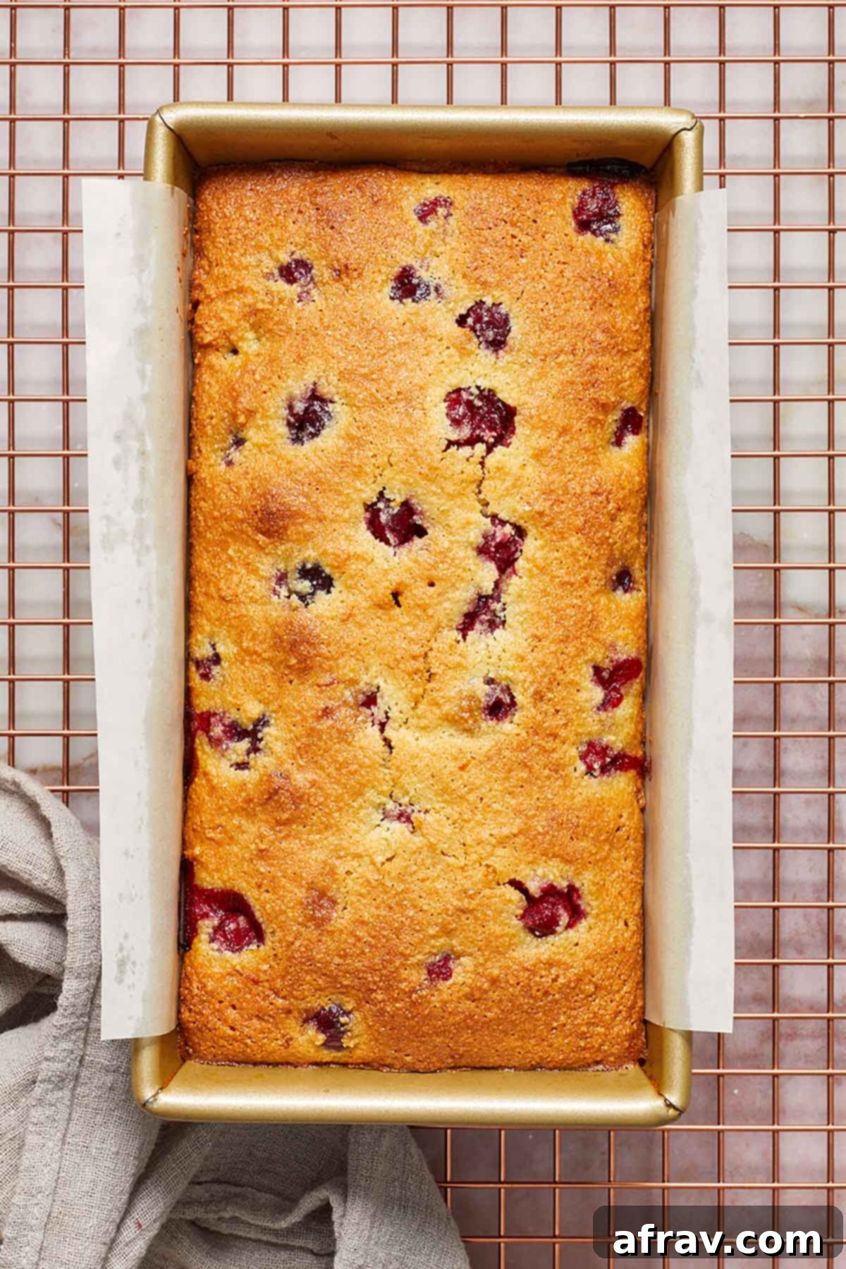 Overhead shot of the freshly baked cranberry orange bread cooling on a wire rack after being removed from the pan.